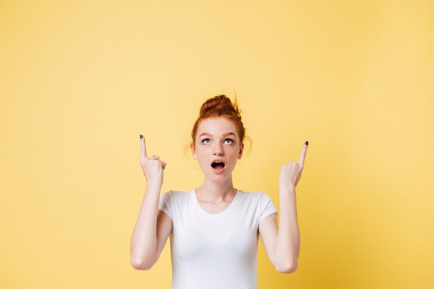 Shocked ginger woman pointing and looking up