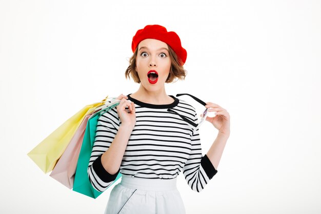 Shocked ginger woman with packages looking at the camera over grey