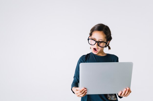 Shocked girl in glasses using laptop