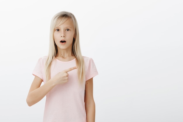 Shocked girl pointing right and drop jaw astonished