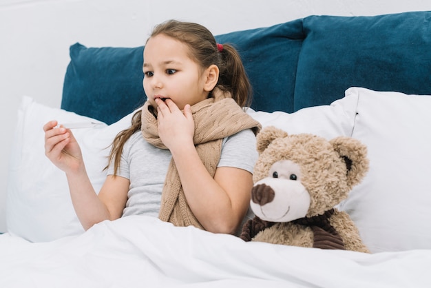 Free photo shocked girl suffering from the cold and fever looking at thermometer