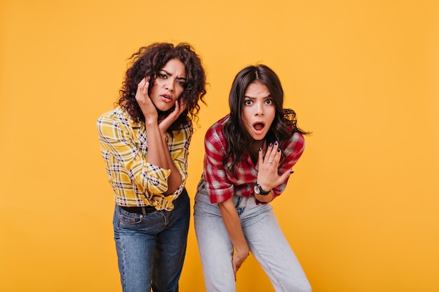 Free photo shocked girlfriends look with indignation and conviction. girl in red blouse opened her mouth in surprise.