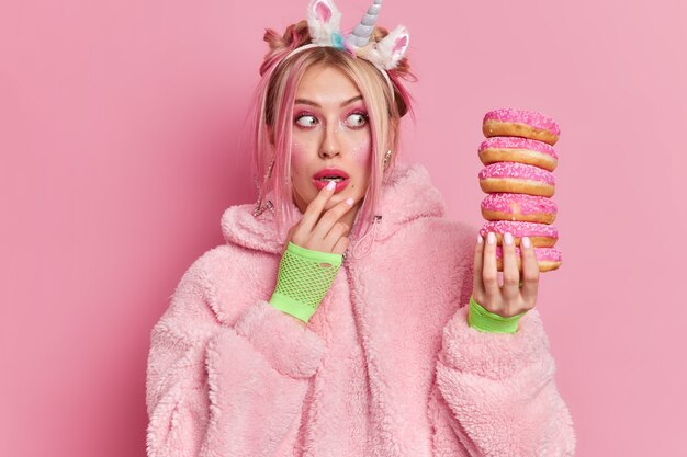 Shocked good looking woman stares at pile of doughnuts realizes how much calories she is going to eat