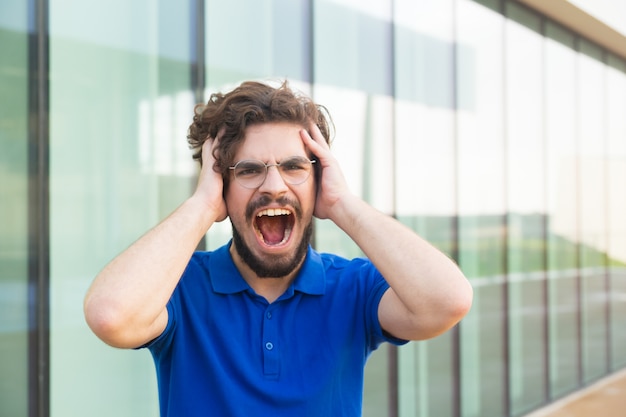 Free photo shocked guy holding head, shouting loud