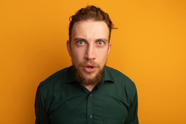 Free photo shocked handsome blonde man looks at front isolated on orange wall