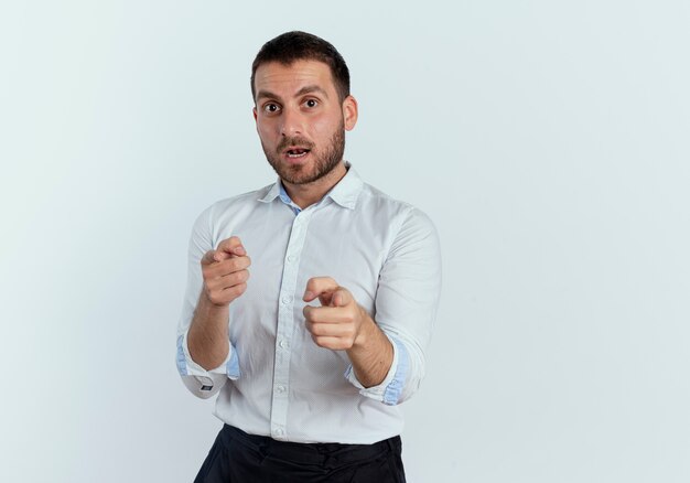 Shocked handsome man points with two hands isolated on white wall