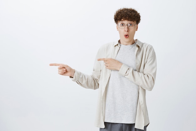 Shocked and impressed teenage guy posing against the white wall