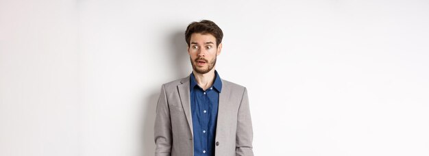 Free photo shocked male entrepreneur in suit looking aside at logo with startled face standing on white backgro