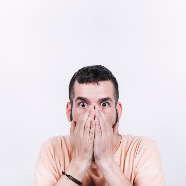Free photo shocked man covering mouth and looking at camera