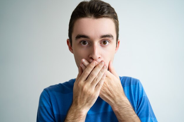 Shocked man covering mouth with both hands