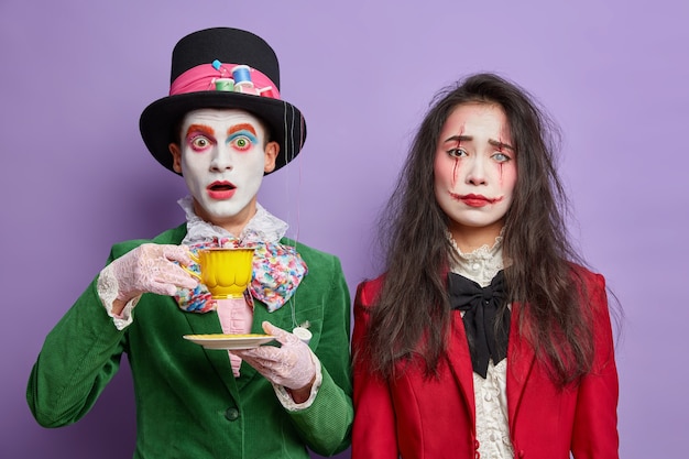 Shocked man has image of mad hatter spends free time on tea party stares surprised wears professional makeup