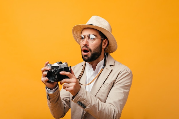 Shocked man in stylish outfit posing with retro camera