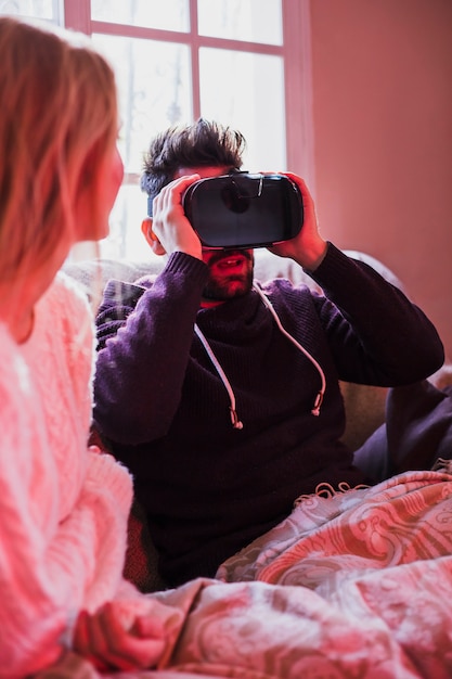 Shocked man using VR headset near girlfriend
