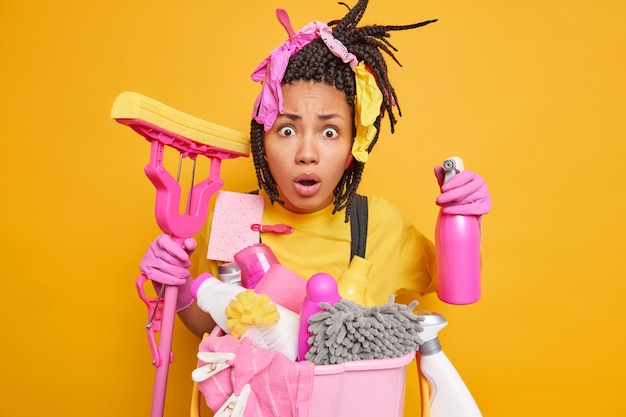 Shocked nervous woman poses with detergent and cleaning accessories