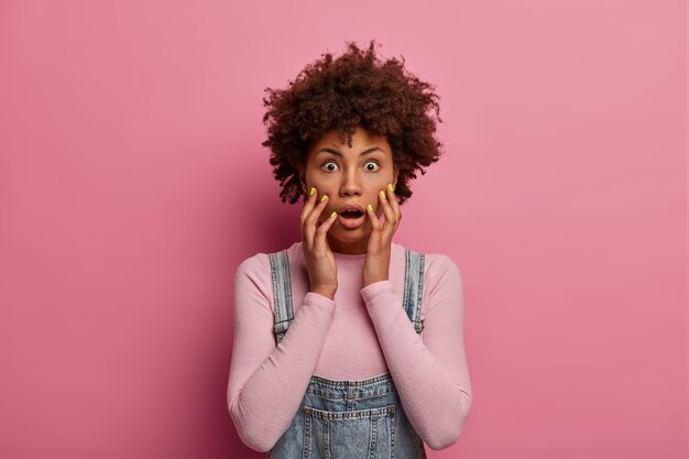 Shocked panic Afro American woman excited by unexpected news, grabs face