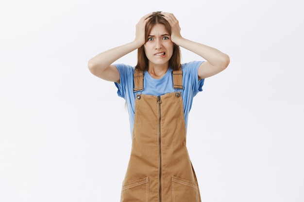 Free photo shocked panicking woman grab head and looking anxious, have big problem