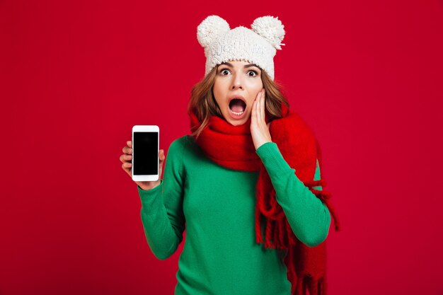 Shocked pretty young woman wearing hat and scarf