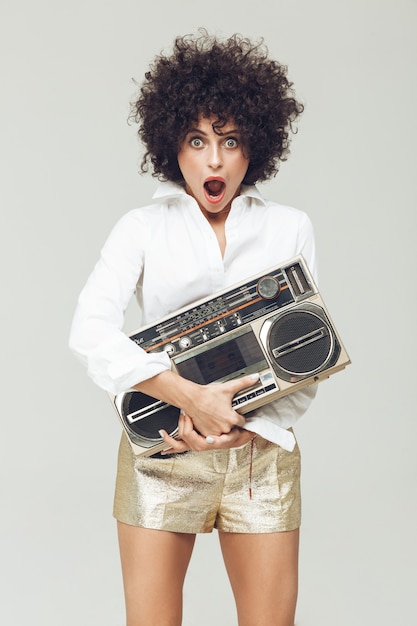 Free photo shocked retro woman holding boombox.