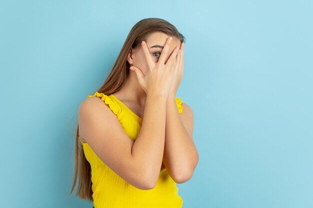 Shocked, scared. Caucasian teen girl's portrait isolated on blue