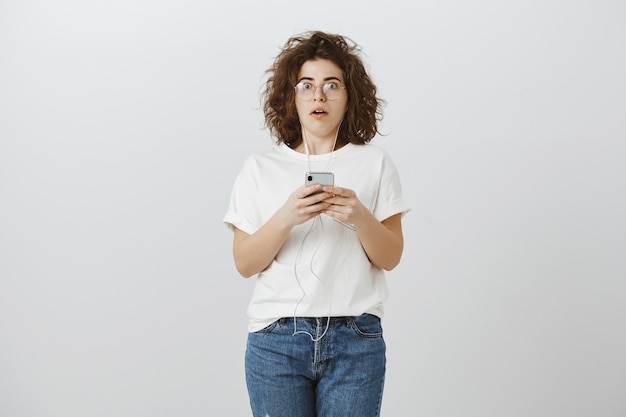 Shocked startled girl standing in stupor after reading message on phone