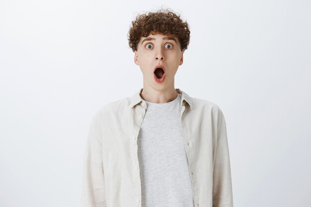 Shocked teenage guy posing against the white wall