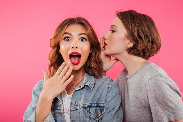 Shocked two women friends gossiping.