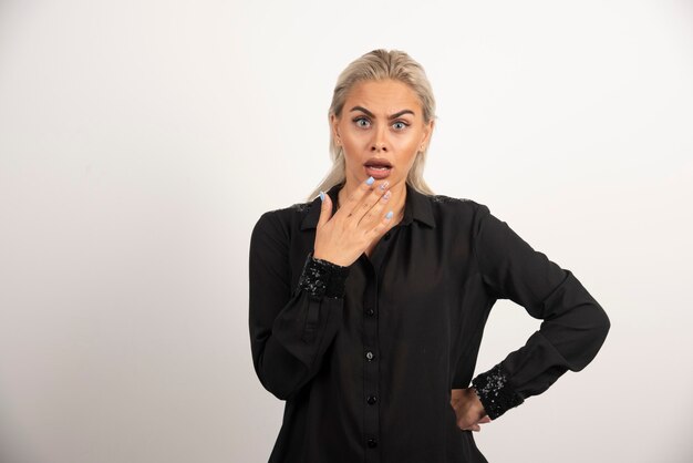 Shocked woman in black shirt posing on white background. High quality photo