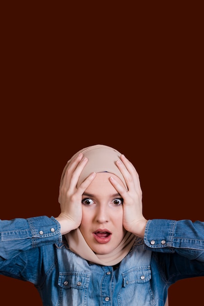 Shocked woman holding her head over dark surface