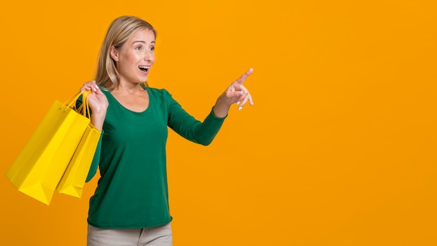 Shocked woman holding many shopping bags and pointing at possible store