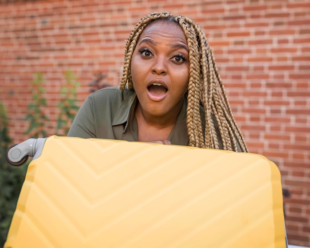 Shocked woman holding a yellow luggage