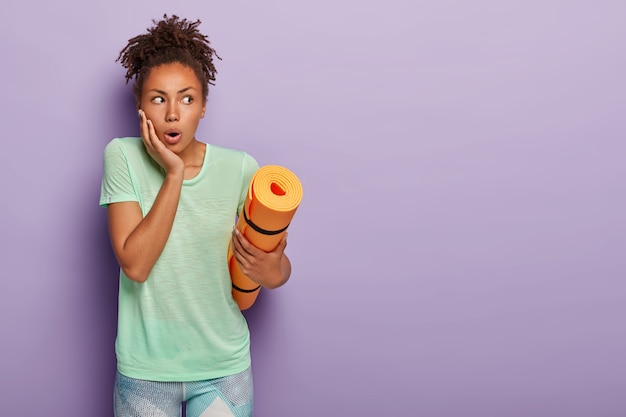 Free photo shocked woman holds yoga mat