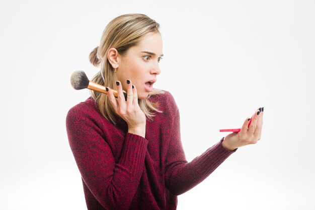 Shocked woman looking in small mirror