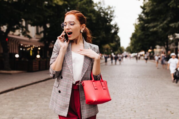 Shocked woman in plaid jacket talking on phone