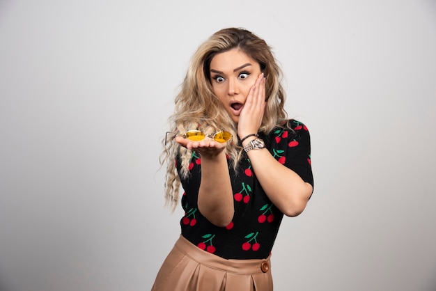 A shocked woman presenting glasses on the hand. 