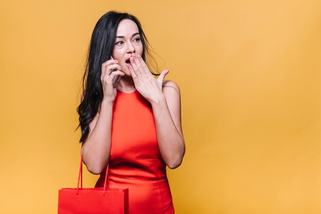 Shocked woman speaking on phone while shopping