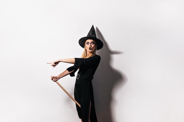 Бесплатное фото Шокированная женщина с черными губами позирует на карнавале. эмоциональная девушка в костюме ведьмы празднует хэллоуин.
