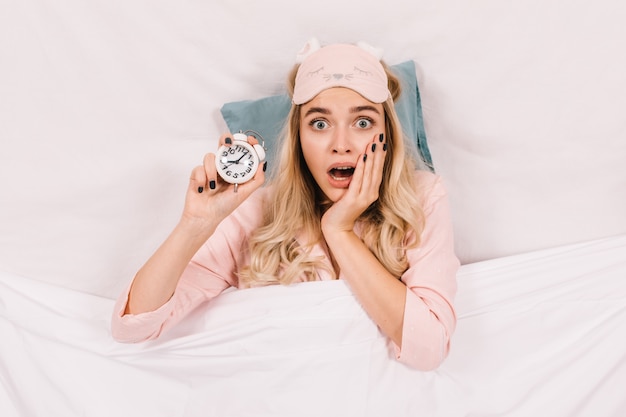 Free photo shocked woman with clock posing with mouth open