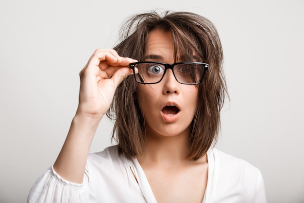 Shocked woman with tousled messy haircut look through glasses