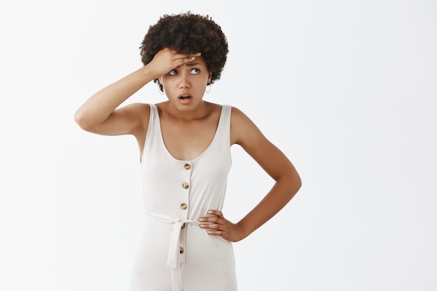 Shocked and worried stylish girl posing against the white wall