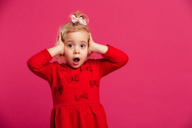 Free photo shocked young blonde girl in red dress holding her head