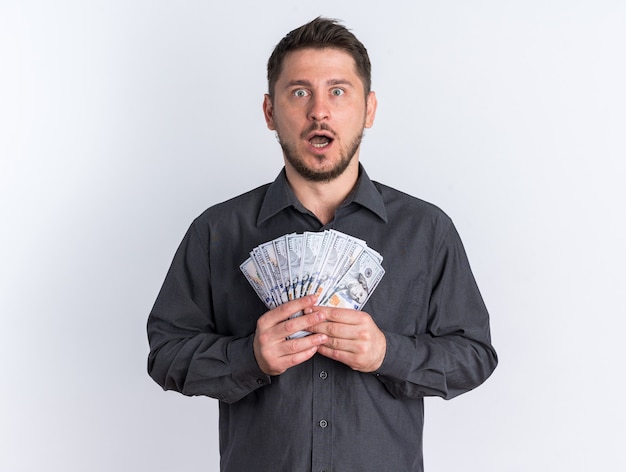 Free photo shocked young blonde handsome man holding money with open mouth looking at camera