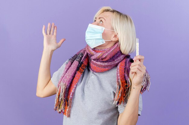 Shocked young blonde ill slavic woman wearing medical mask and scarf