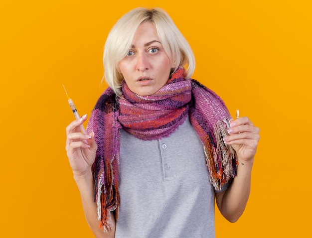 Шокированная молодая блондинка больна славянская женщина в шарфе держит шприц