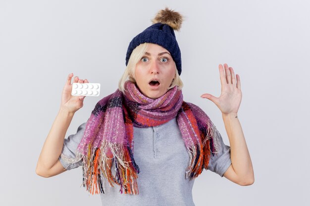 Shocked young blonde ill slavic woman wearing winter hat and scarf