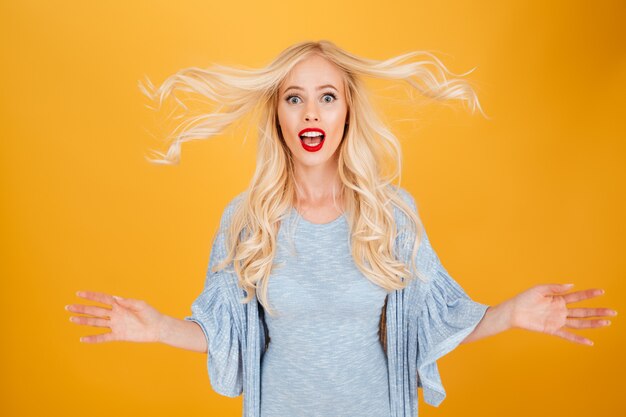 Free photo shocked young blonde woman shaking hair.