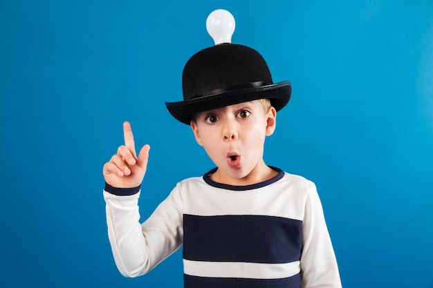 Free photo shocked young boy in hat with lightbulb having idea