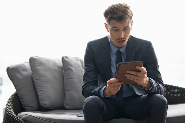 Shocked Young Businessman Looking at Tablet