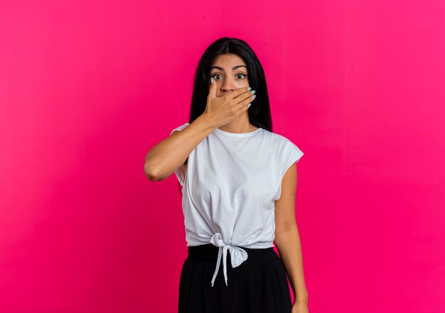 Shocked young caucasian woman puts hand on mouth looking at camera