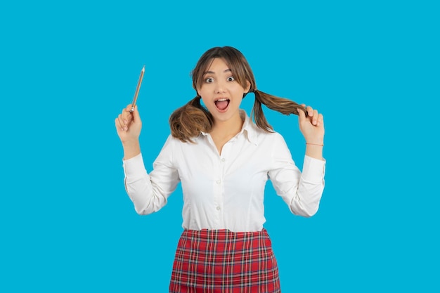 Shocked young college girl holding pen and straighten her hair. High quality photo