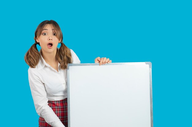 Shocked young college girl holding white idea board. High quality photo